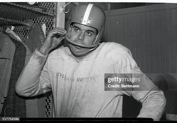 Otto Graham, star quarterback of the Cleveland Browns, holds the face guard attached to his helmet. He and other players in the National Football...