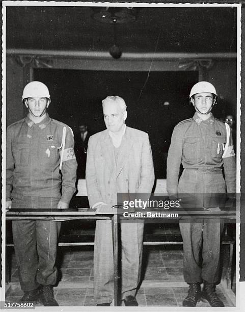 Dr. Morteza Yazdi, one of the principal founders of the Communist Party of Iran, stands between two military guards as he hears the judge at a...