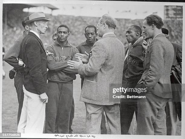 Avery Brubdage, president of the United States Olympic committee, is shown with back to camera exposulating with field judge who disqualified the...