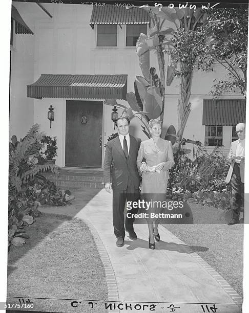 Walking Along Together. Hollywood, Calif.: To the tune of popping flashbulbs, Rita Hayworth and Aly Khan stroll arm in arm towards waiting newsmen to...
