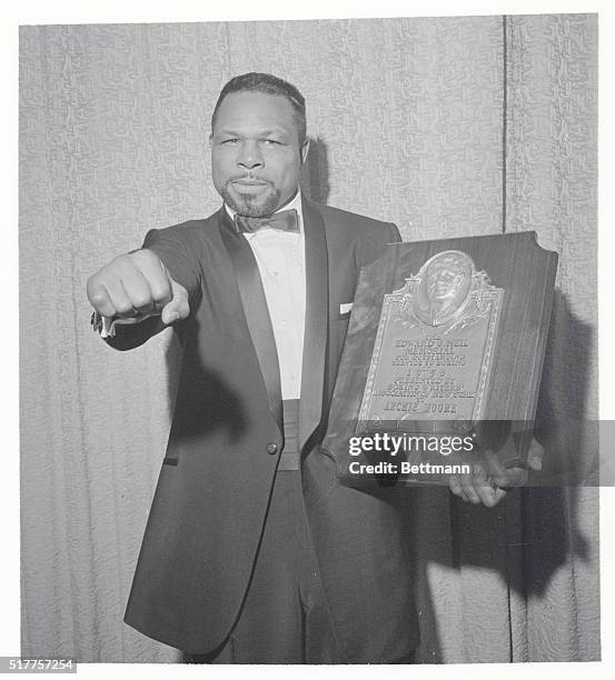 New York: Moore Honored. Boxer Archie Moore displays the powerful right that helped earn him the Edward J. Neil Plaque presented to him at the Boxing...