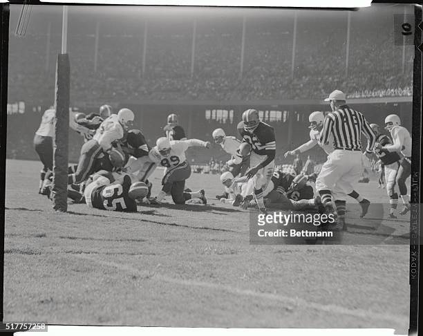 Jim Brown, Cleveland Browns fullback, eludes two Chicago Cardinal tacklers as he gains eleven yards in the second quarter of Browns-Cards action....