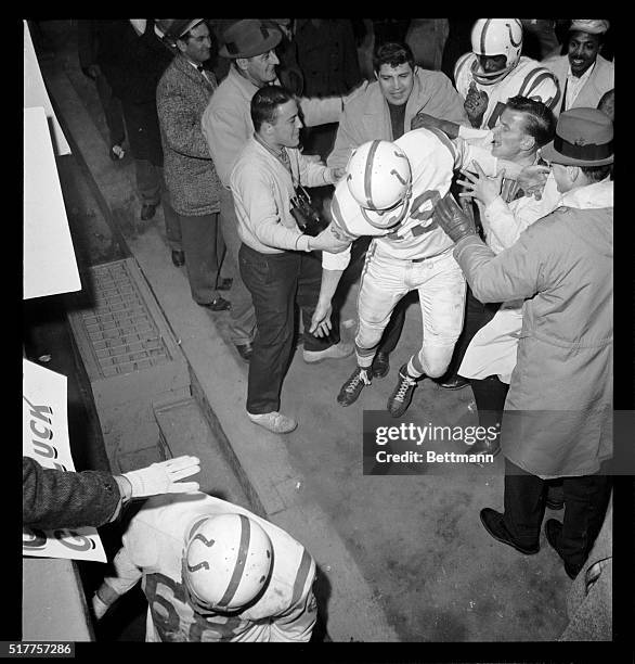 Baltimore Colts Quarterback, Johnny Unitas, is mobbed by well-wishers as he heads for the dressing room after leading Colts to a 23-17 win over the...