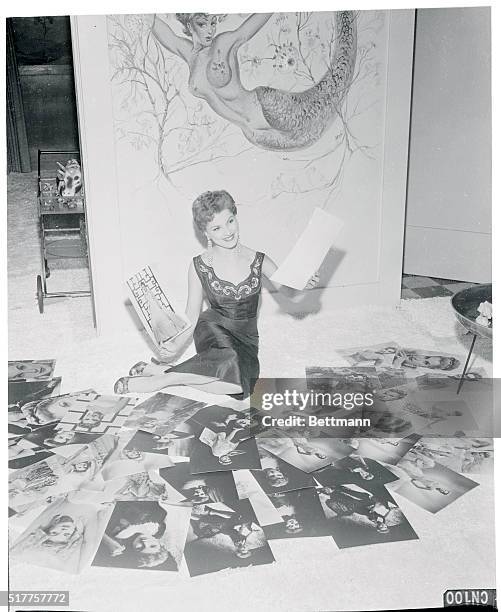 Screen queen Debra Paget looks over the latest batch of proofs from her studio's still gallery. She selects and approves the ones she likes best...