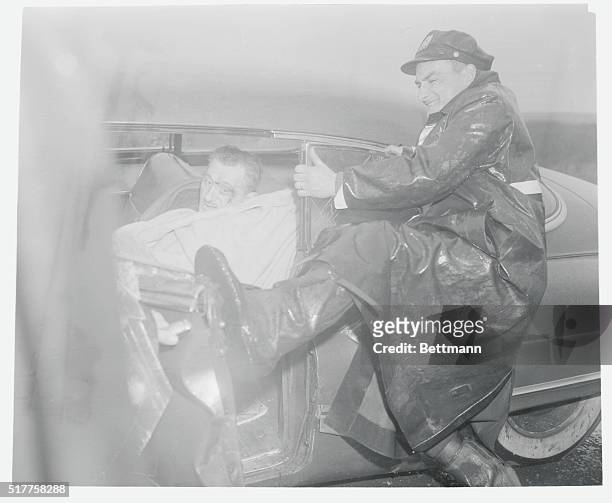 His face contorted by the effort, an unidentified policeman strains to open the door of a wrecked auto on the Belt Parkway here March 6th to free...