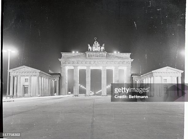 Brightly illuminated by searchlights, the famed Brandenburg Gate looms impressively in the night in East Berlin. The gate stands in the Eastern...