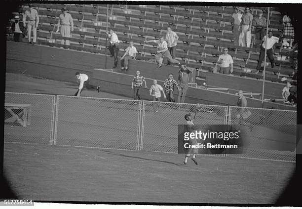 Hank Aaron of the Milwaukee Braves leaps high against the right field wall to catch a long drive by the Dodger Junior Gilliam, in the explosive ninth...