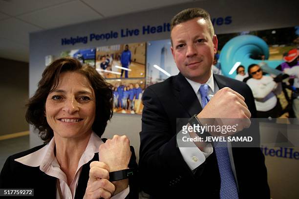 United Healthcare executives Jean McGann and Chuck Cerniglia pose wearing special activity trackers at their office in New York on March 24, 2016....