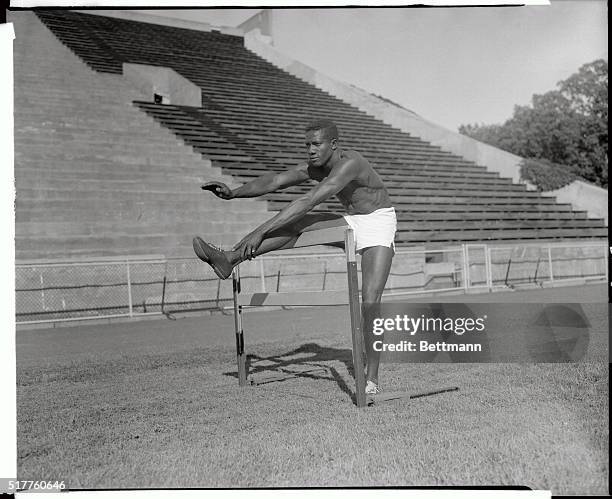 This photograph shows Roland Blackman, the 400 Meter low hurdler, exercising leg on hurdle.