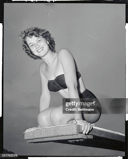 Cypress Gardens, Florida: Lovely Joan Faye Binette of New Hampshire, who has been named "Miss Diving Girl of 1956" is shown perched atop a diving...