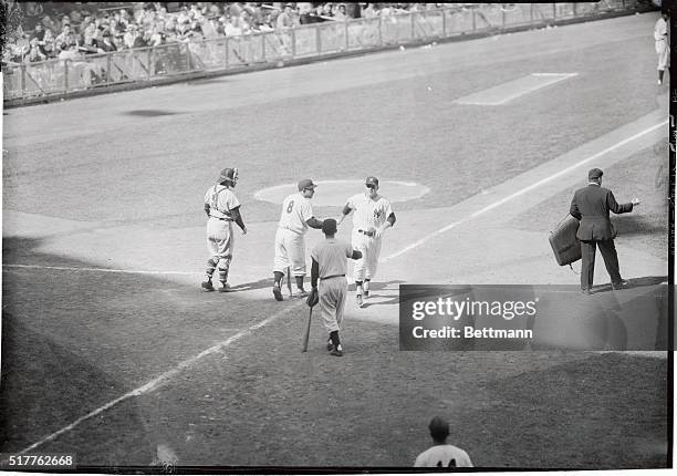 Mickey Mantle of the Yankees, scoring on his second homer in today's game with the Kansas City athletics, is greeted at the plate by Yogi Berra and...