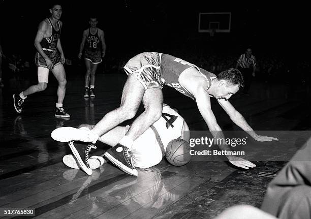 Boston's Bob Cousy goes sailing over New York's Carl Braun , while trying to snag a loose ball during the fourth quarter of their game at Madison...