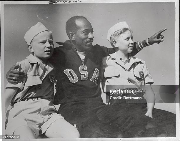 Harrison Dillard, who won the 100 Meters event in the 1948 Olympics and who was in the high hurdles in 1952, is shown with two uniformed Olympic...