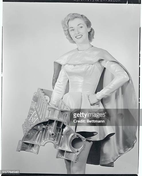 Pretty "Maid of Aluminum," Jean Moorehead, demonstrates lightness of new die cast aluminum engine block by lifting it with one hand. The automobile...