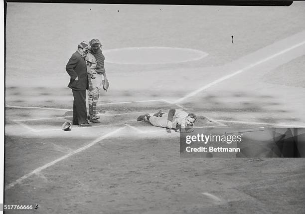 Sprawled on the ground, Yankee catcher Yogi Berra's face registers pain after he was hit on the right arm, above the elbow by Dodger pitcher Billy...