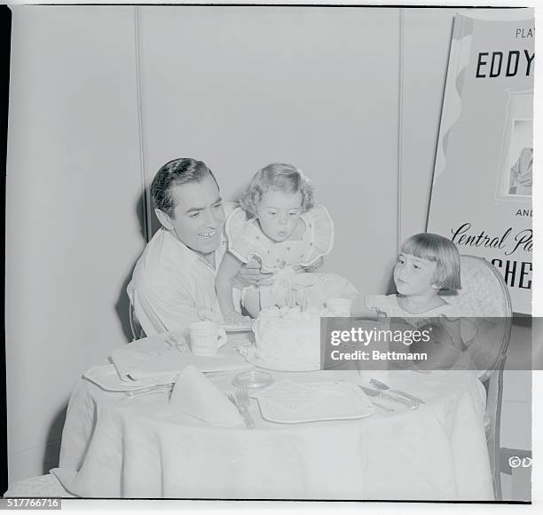 Hollywood, California: Two Candle Birthday--Actor Tyrone Power holds up his little daughter, Taryn, to let her blow out the candles on the cake that...