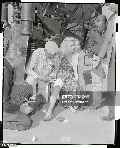 Actress Mamie Van Doren's shapely thigh is treated by first aid man Nathan Stufflebeam, after it was lacerated during the shooting of a scene in the...