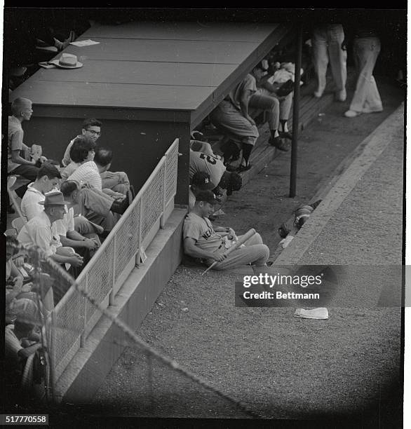 New York Yankees' Mickey Mantle, who injured his left knee in a game on Sunday, amuses himself by pounding pieces of a bat into the ground beside the...