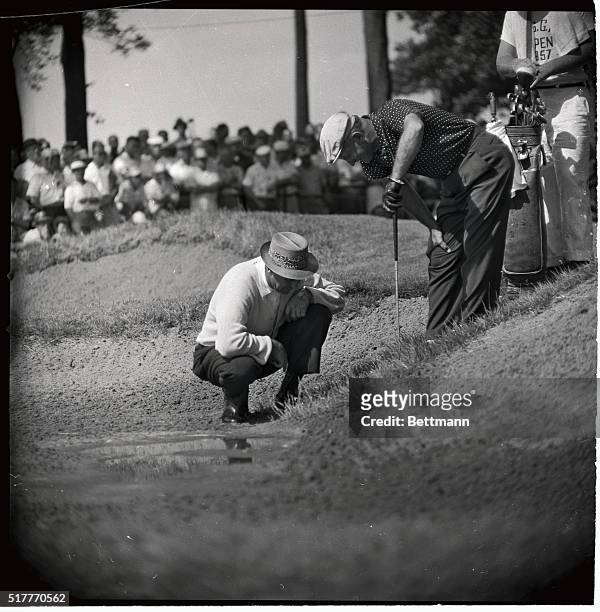 Sam Snead, of White Sulpher Springs, Virginia, is shown squatting as he examined his ball, embedded in the grass at rain-swept Inverness golf course...