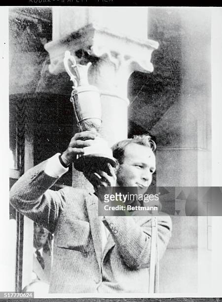 America's Arnold Palmer holds aloft his trophy after winning the British Open Golf Championships here July 13th. Palmer shot a course-record 67 and a...