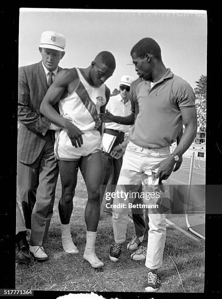 Florida A&M track star Bob Hayes is aided by teammates after he pulled a muscle in his left leg during the running of the 100-meter dash at the...