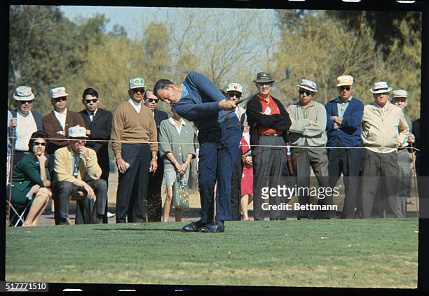 Phoenix, AZ: Billy Casper at the Phoenix Open. Also shown with golfer Don January,as they pause on 7th green while plane flies overhead.