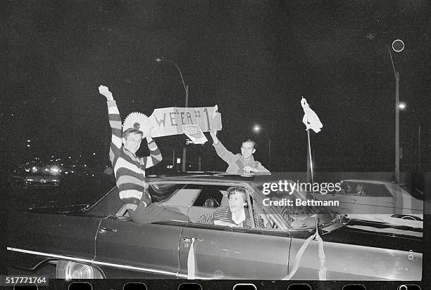 Boston: Happy Red Sox fans, holding sign with Boston team photo attached, whoop it up after the Red Sox won the American League pennant.