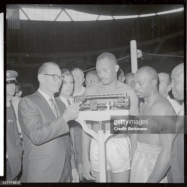 Oakland, Calif.: Welterweight Champion Curtis Cokes, Dallas, Tex., stands on scales as Bob Turley , Calif. State Boxing Commission, calls out his...