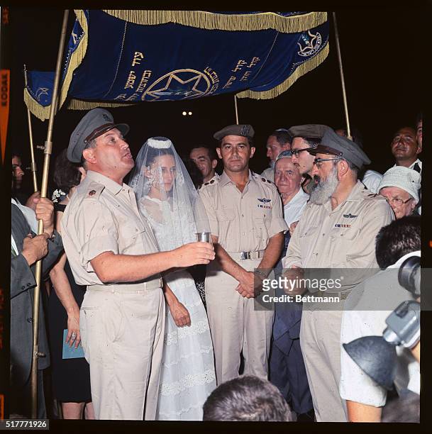 Yael Dayan, daughter of Israeli Defense Minister, Moshe Dayan, stands under hand-held canopy during marriage ceremony, July 22nd. Shlomo Goren, chief...
