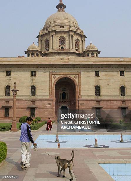 Picture taken 25 October 2004 in New Delhi shows an Indian caretaker patrolling around the cabinet secretariat building with a langur monkey, chasing...
