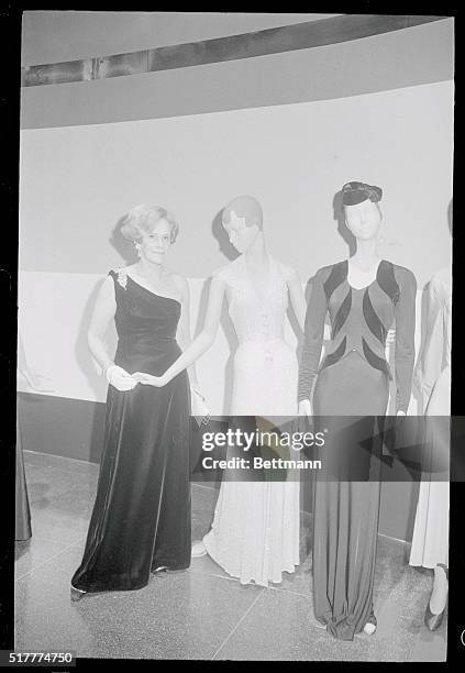 Fashion in history...Wearing a one-shoulder, black velvet evening gown, Mrs. Sophie Gimbel stands by a mannequin that is draped with a gown she...