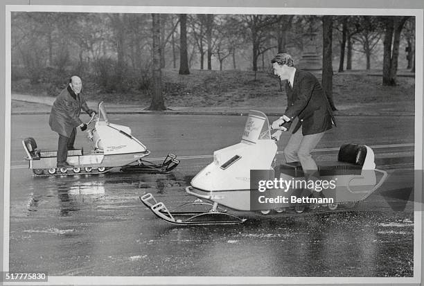 New York: Stirling Moss and Dan Gurney, big names in the auto racing world, scoot around New York's icy Central Park on snowmobiles January 29th....
