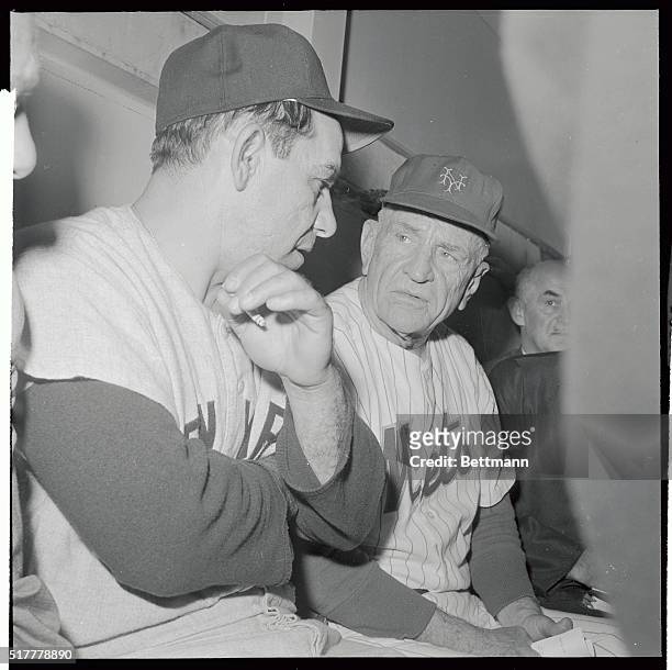New York Yankee manager Yogi Berra , and New York Met's pilot Casey Stengel chat with newsmen in dugout after rain and a sudden thunderstorm caused...