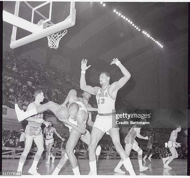 Philadelphia: 76er Lucious Jackson comes down hard with a rebound. 76er Wilt Chamberlain keeps out of his way as the players in the rear start up...