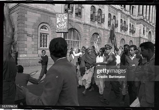 Battered bus stands in as a police paddy wagon to carry off banner-waving Communists in Calcutta. The demonstrators were rounded up during a mass...