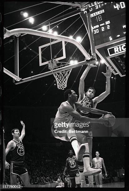 Laker forward Elgin Baylor, caught behind the backboard, jump-passes around San Francisco's Dale Schlueter before going out of bounds in the first...