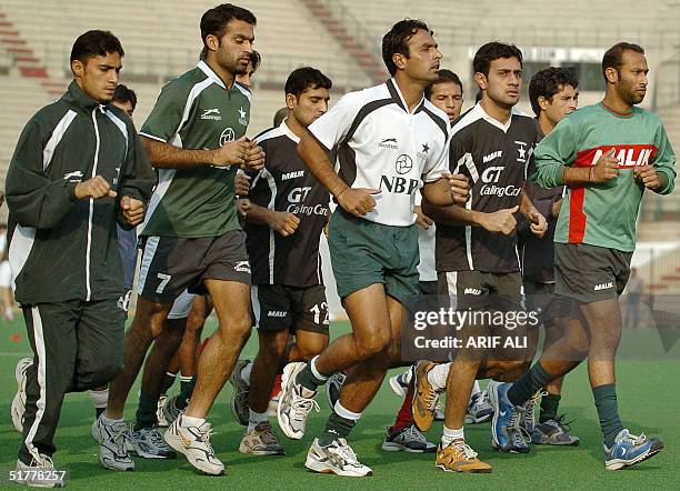 Pakistani field hockey players warm up during a practice session at National Hockey Stadium in Lahore, 23 November 2004, as they prepare for the...