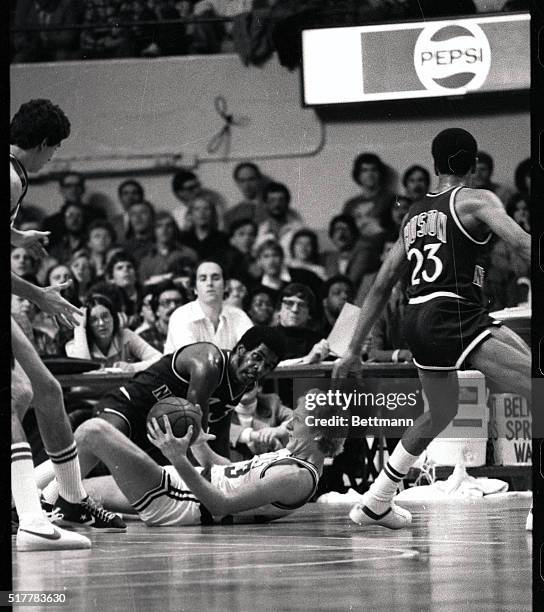 Celtics' Larry Bird, lying on his back, and holding the ball, prepares to pass off to a teammate as the Knicks' Toby Knight looks on during second...