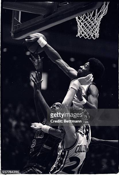 76ers' Julius Erving reaches above teammate Doug Collins and Bucks Junior Bridgeman to knock away a rebound in first half action at the Spectrum in...