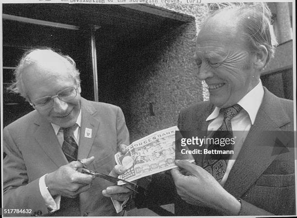 Norwegian Premier Odvar Nordli holds a Norwegian 1000 crowns bill as Minister of Finance, Per Kieppe, with a scissor cuts a small piece of the bill...