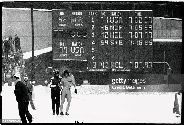 Eric Heiden, of the United States, his gol-medal winning time displayed on the board behind him, is congratulated by a friend after winning his heat...