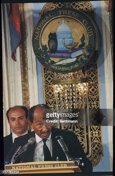 Addressing the National Press Club while standing beneath their insignia is Egyptian President Anwar Sadat.