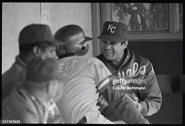 Royals' manager Dick Howser, still seeking his first playoff win with Kansas City, finds something to smile about during dugout chat with George...