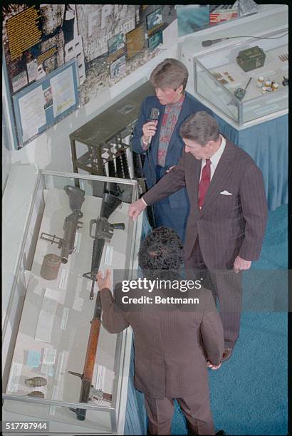 Washington, DC: President Reagan views a collection of weapons supplied to leftist guerrillas by Nicaragua on display in the lobby of the State...