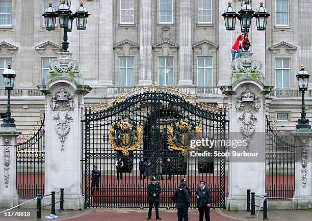 British police officers looks on as a Fathers 4 Justice protestor dressed as Father Christmas has chained himself to the top of the gates of...