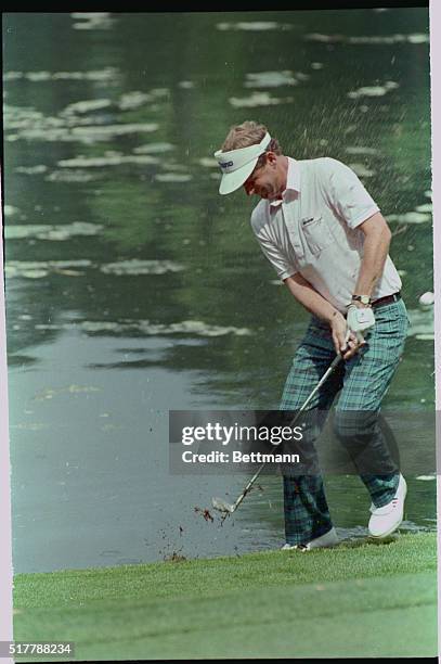 Augusta, Georgia: Scotland's Sandy Lyle, the leading money-winner on the U. S. Tour, tries to avoid the spray as he blasts from the edge of a pond...