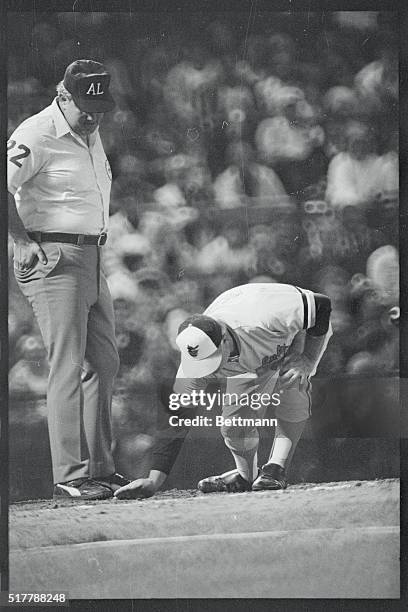 Umpire Larry Burnett watches as Baltimore Orioles' manager Earl Weaver covers home plate with dirt after being thrown out of the game by umpire Rocky...