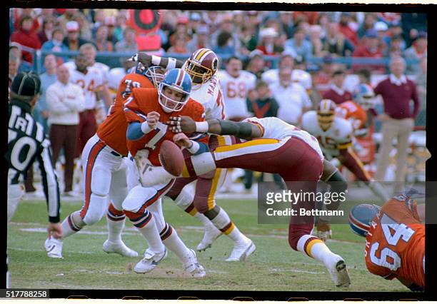 Denver quarterback John Elway fumbles the ball after running into the utstretched leg of Redskins defensive end Charles Mann during first quarter...