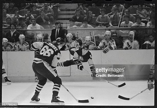Pittsburgh Penguin's Jim Johnson gets knocked into the air by a New York Ranger here, but that doesn't prevent him from passing the puck to teammate...