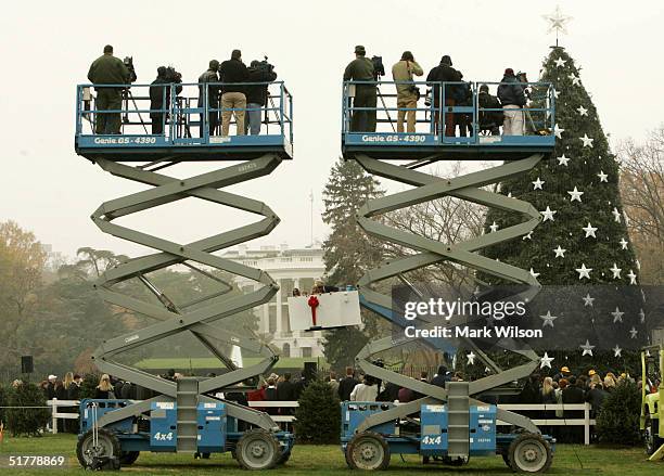 Members of the media stand on hydraulic lifts as Lynne Cheney and Peter Nostrand of the Pageant of Peace descend after placing a star atop of the...